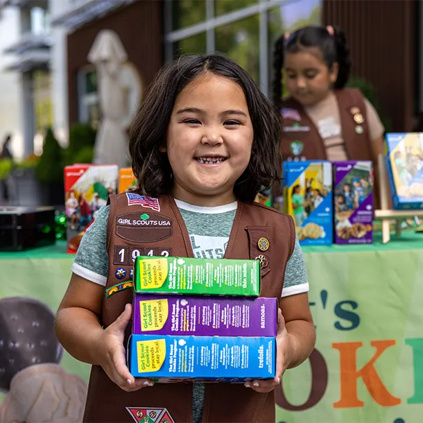 A Girl Scout holding boxes of cookies at a sale